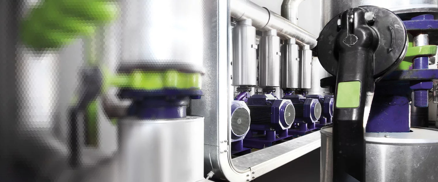  Close-up view of multiple electric motors with connected valves and piping in an automated industrial system.