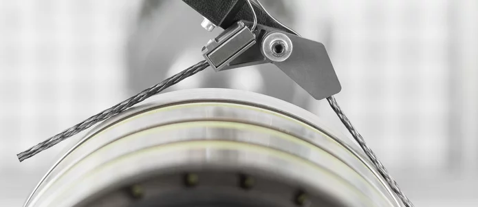  Close-up of a mounted electrical sliding contact with carbon brush and braided wire connection on a rotating slip ring.