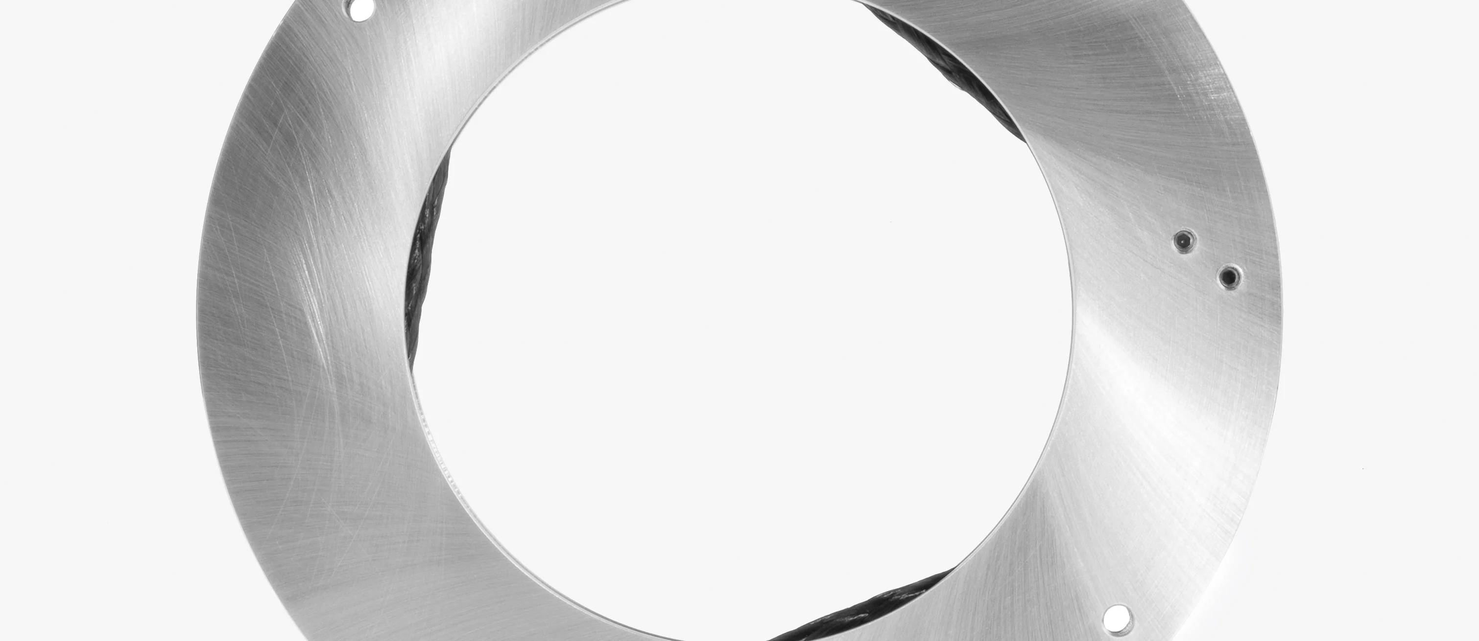  Technical close-up of a circular metal housing with integrated braided wires, used in slip ring or power transfer systems.