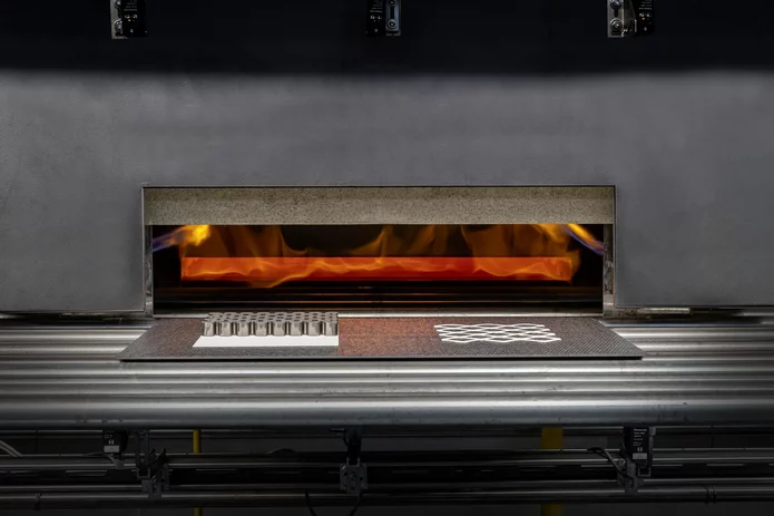  Industrieller Ofen mit sichtbarer Flamme zur thermischen Behandlung von Bauteilen aus technischer Keramik oder Metall auf einem Fördersystem.