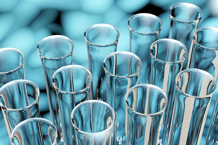  Gruppe transparenter Glas-Reagenzgläser vor unscharfem Hintergrund mit blauen Tabletten – Laborbedarf für pharmazeutische Tests.