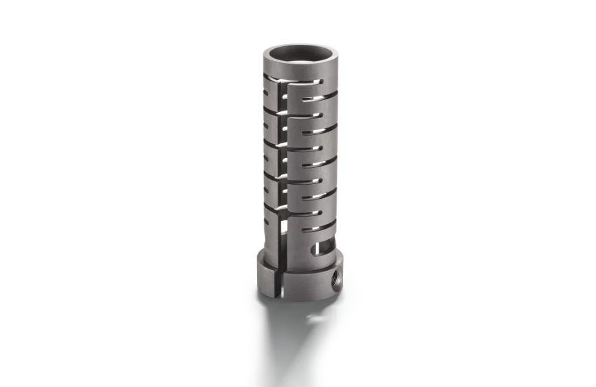  Cylindrical precision metal component with continuous slot structure, designed for technical applications in mechanical engineering or medical technology.