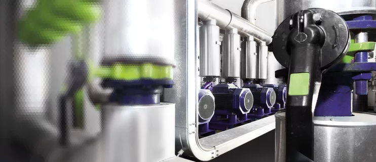  Detailansicht mehrerer Elektromotoren mit angeschlossenen Ventilen und Rohrleitungen in einer automatisierten Industrieanlage.
