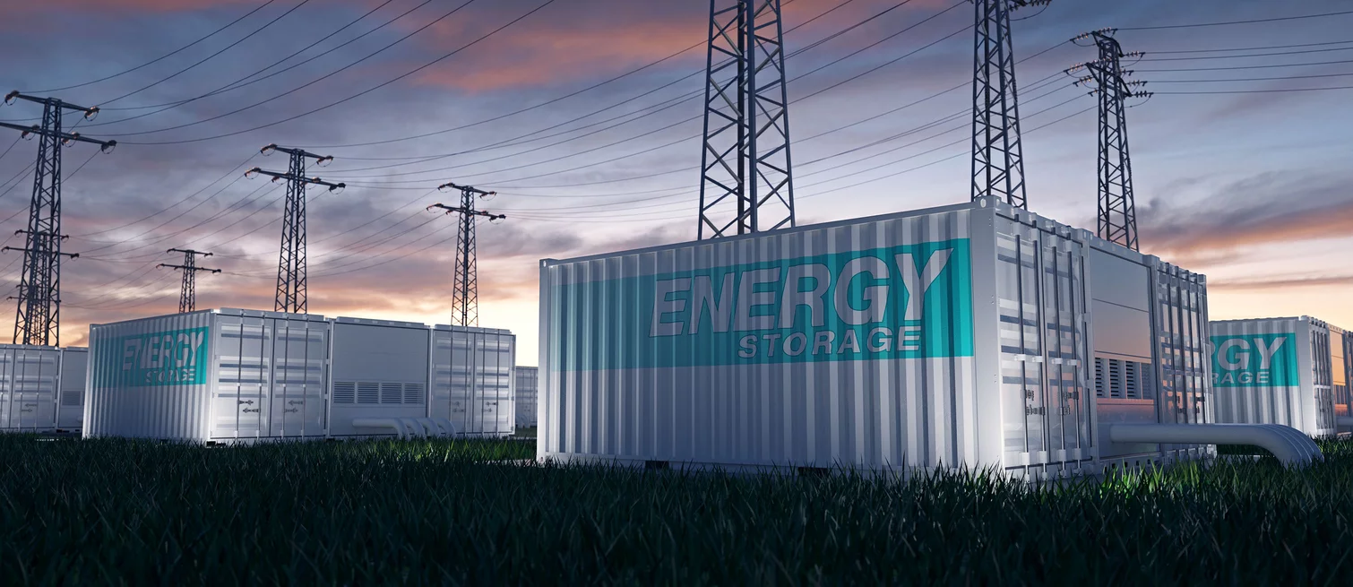  Modern energy storage containers in a field beneath high-voltage power lines at sunset.