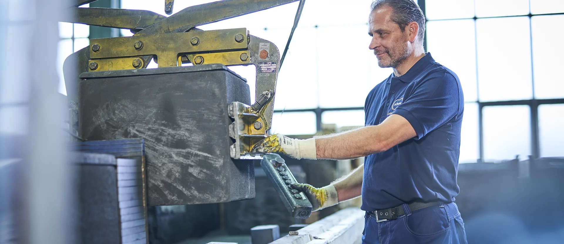  A Schunk Group employee operates a machine control system wearing gloves in the production hall.