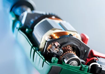  Close-up of an opened electric motor showing copper windings, rotor, and carbon brushes.