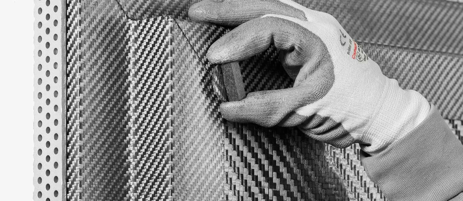  A technician wearing gloves inspects the surface of a carbon fiber reinforced carbon (CFC) component with typical weave texture.