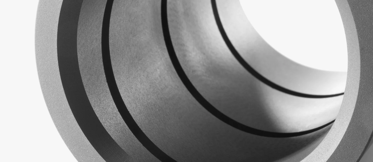  Close-up of a cylindrical component made of technical ceramic or graphite, commonly used as a bearing or sealing element.
