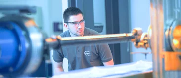 A Schunk employee wearing safety glasses observes a glowing test component in a lab setup for material analysis.
