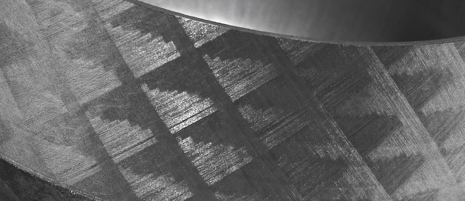 Macro shot of a ground or laminated surface with technical texture, likely made of graphite or composite material.