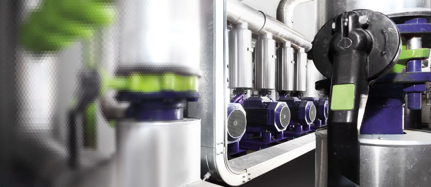  Detailansicht mehrerer Elektromotoren mit angeschlossenen Ventilen und Rohrleitungen in einer automatisierten Industrieanlage.