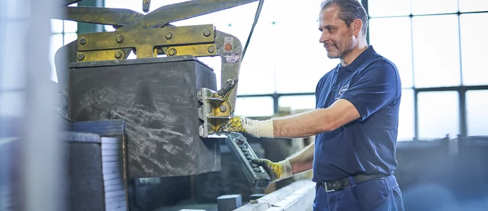  A Schunk Group employee operates a machine control system wearing gloves in the production hall.