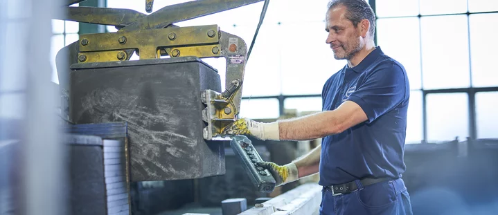 A Schunk Group employee operates a machine control system wearing gloves in the production hall.