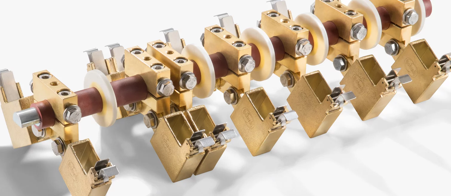 Close-up of an industrial current collector assembly with metal contact elements, insulators, and precision fastening.