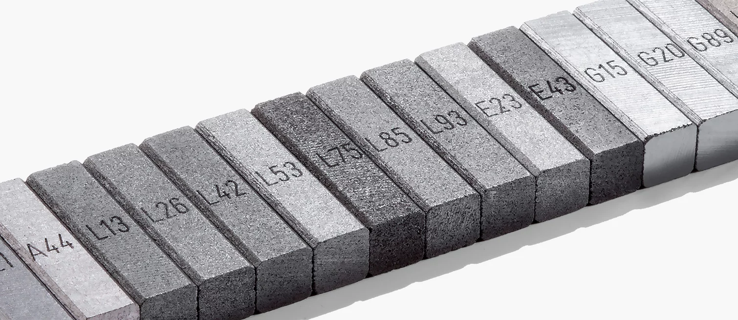  Reihe beschrifteter Graphitproben mit verschiedenen Werkstoffnummern – symbolisch für die Vielfalt industrieller Kohlenstoffmaterialien bei Schunk.