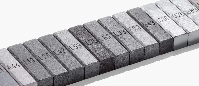  Reihe beschrifteter Graphitproben mit verschiedenen Werkstoffnummern – symbolisch für die Vielfalt industrieller Kohlenstoffmaterialien bei Schunk.