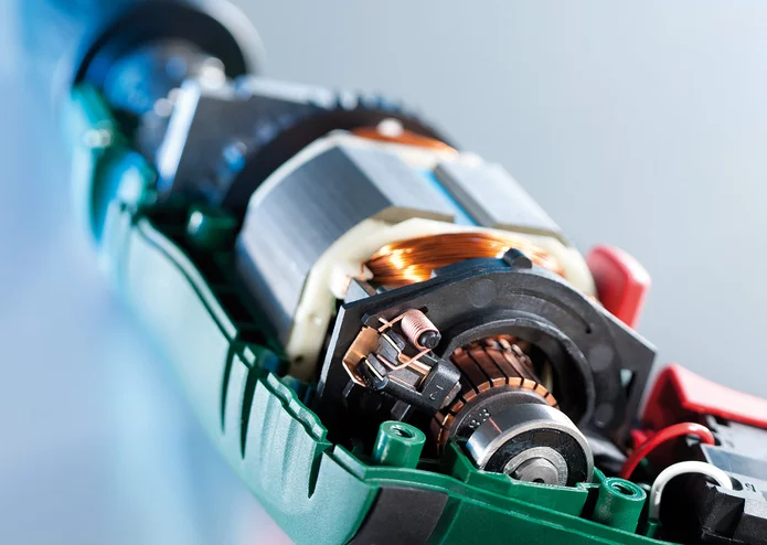  Makroaufnahme des geöffneten Elektromotors mit sichtbarer Kupferwicklung, Anker und Schleifbürsten.