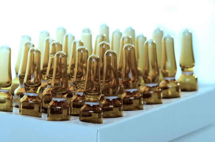  Row of empty brown glass ampoules in packaging – sterile primary packaging for pharmaceuticals.