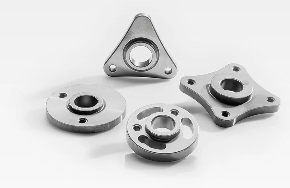  Vier verschiedene Naben aus Metall für Wasserpumpen mit präzisen Formen und Bohrungen, vor weißem Hintergrund