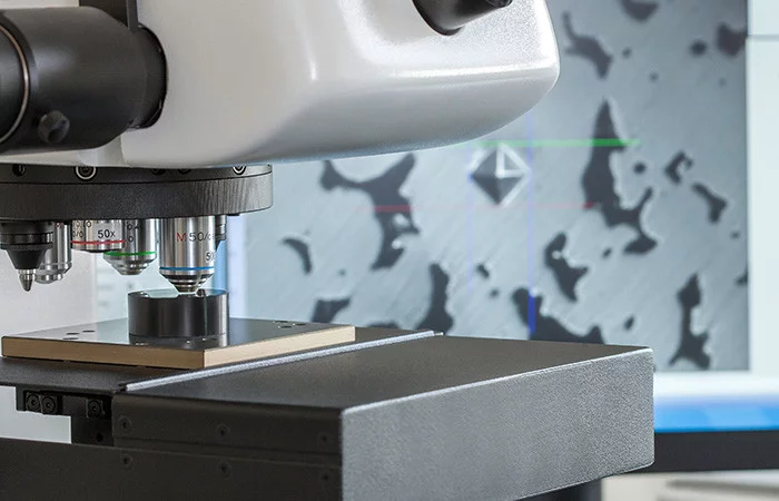  Testing procedure: Close-up of a microscope with a sample plate, microstructure displayed on a screen