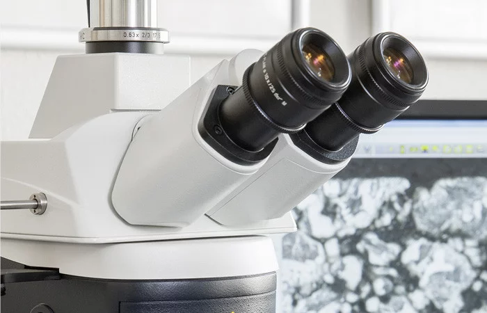  Testing procedure: Close-up of microscope eyepieces, microstructure displayed on a screen in the background