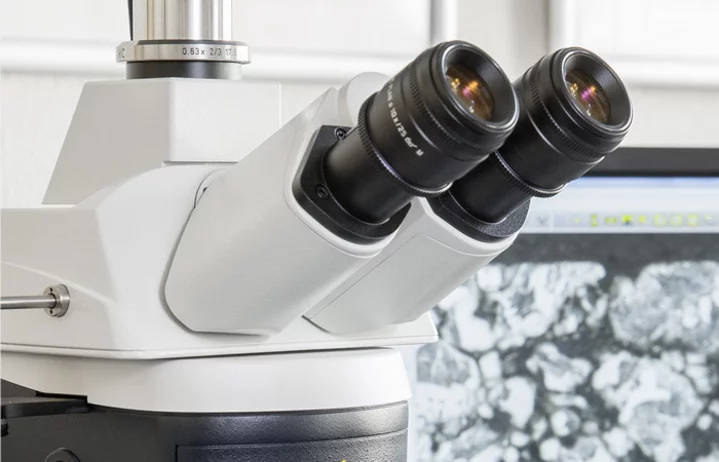 Testing procedure: Close-up of microscope eyepieces, microstructure displayed on a screen in the background