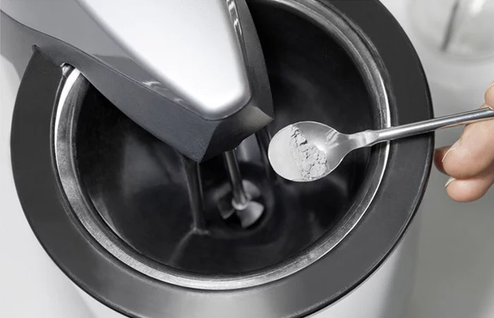  Prüfverfahren: Hand hält Löffel mit Pulver über ein Gerät zur Materialprüfung