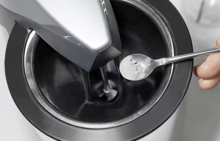 Testing procedure: Hand holding a spoon with powder above a material testing device