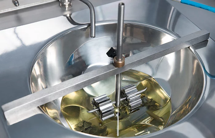  Prüfverfahren: Metallische Vorrichtung in einer Schale mit gelber Flüssigkeit