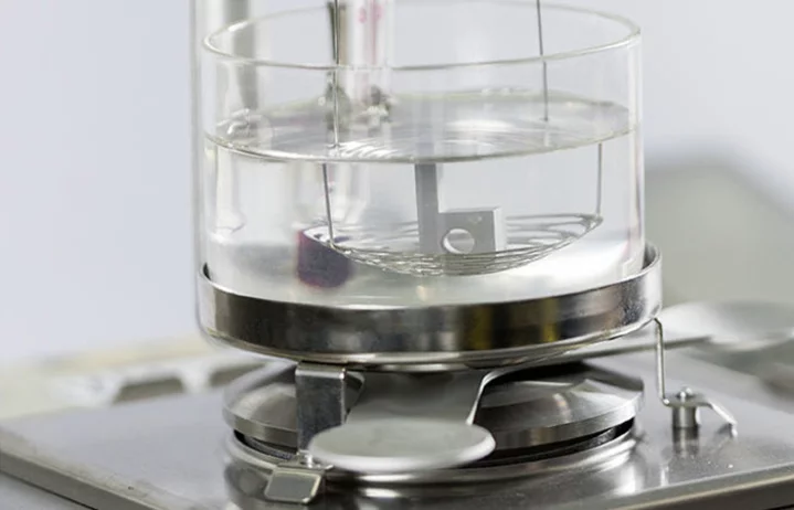 Testing procedure: Glass chamber with wire rack and metallic component, placed on a scale in a laboratory