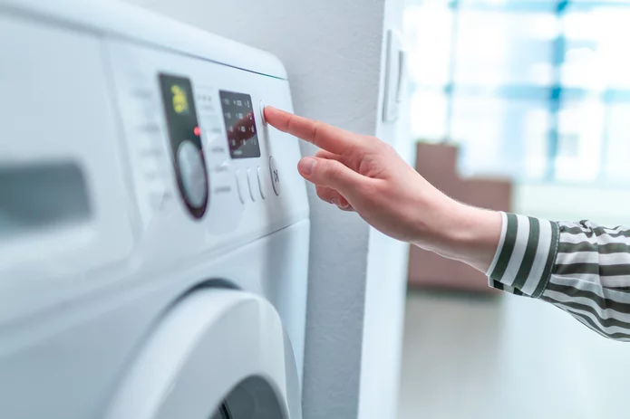  Hand bedient das Kontrollpanel einer modernen Waschmaschine oder eines Trockners