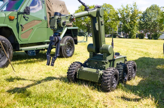  Unmanned mobile robot with a manipulator arm next to an armored response vehicle