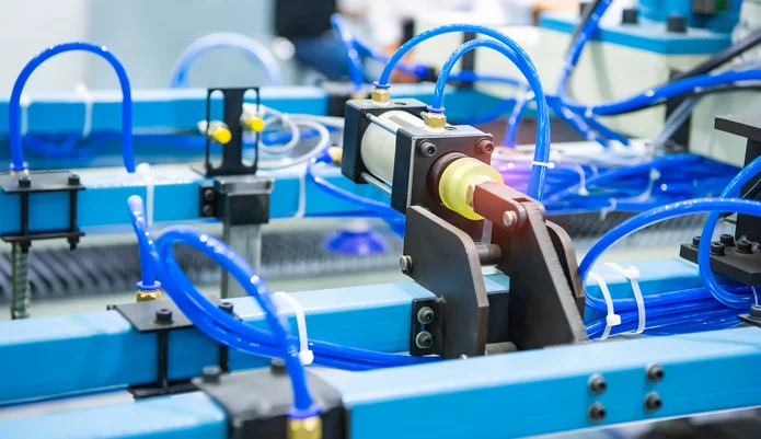  Pneumatischer Aktor mit blauen Druckluftschläuchen in einer automatisierten Industrieanlage