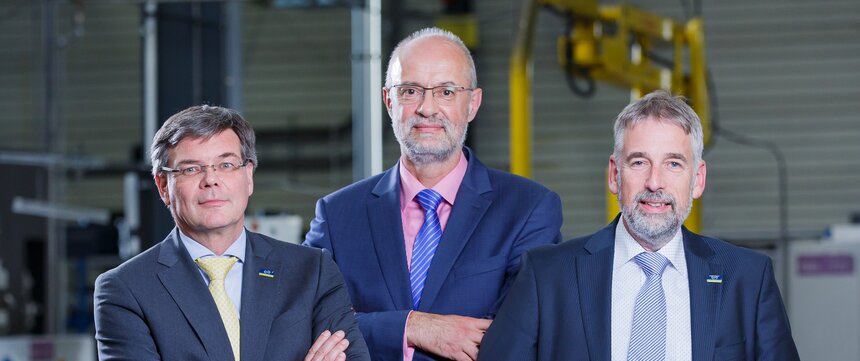  three men in suits standing and looking into the camera