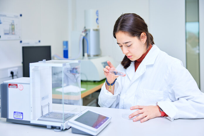 A researcher in a laboratory examining a sample. Focus on research, development, and innovative technologies at Schunk.