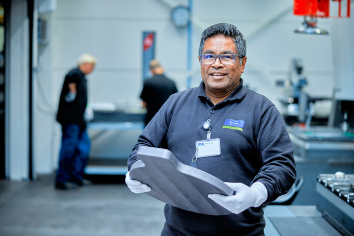 A Schunk employee in a production area holding a component. Focus on customer satisfaction and high-quality manufacturing.