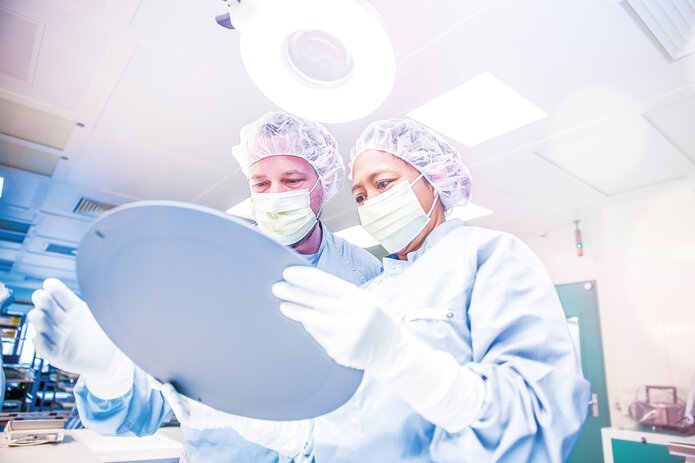 two employees in safety clothing and smocks at work