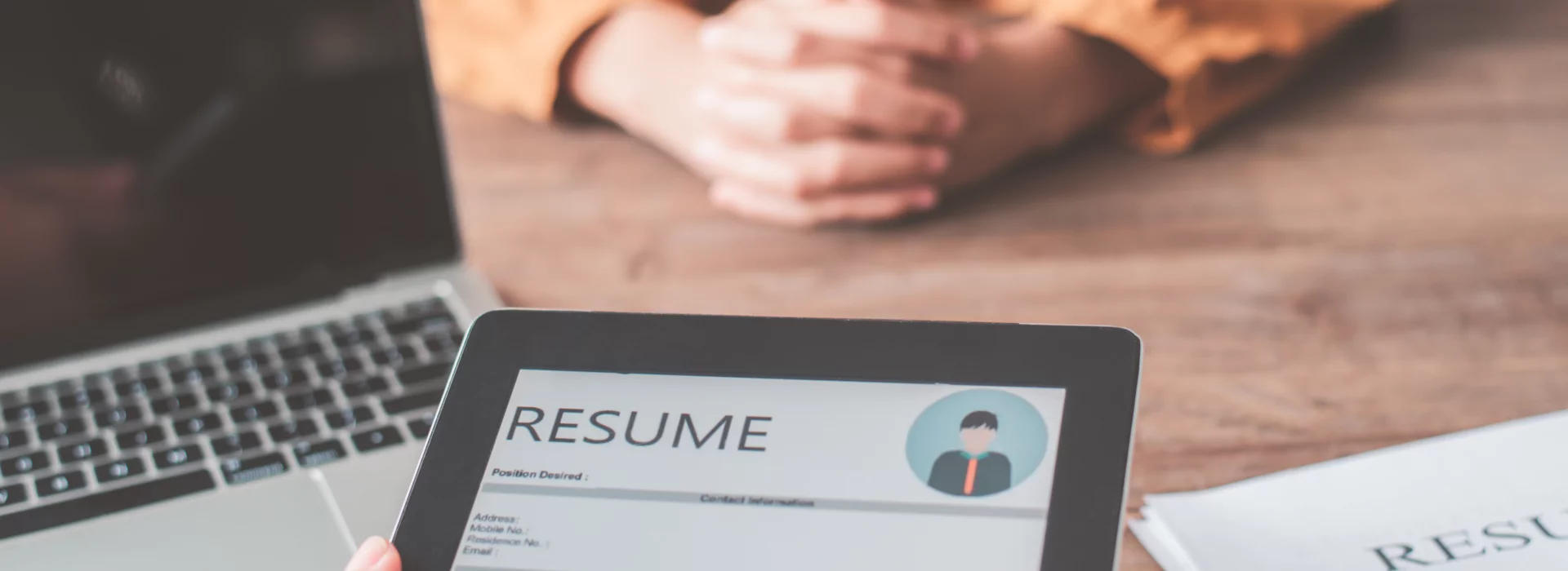 During an interview, the HR manager reads the applicant's CV on a tablet.