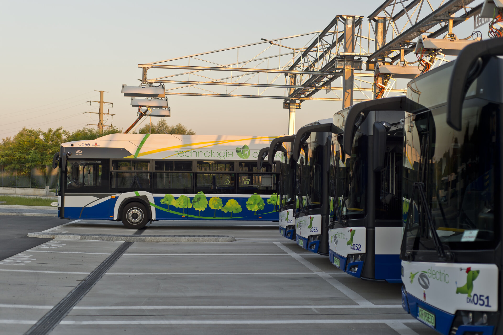Multiple electric buses at a charging station with Schunk pantographs, one bus currently charging.