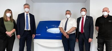 5 Personen stehen um Korrosionsprüfanlage herum und schauen in die Kamera