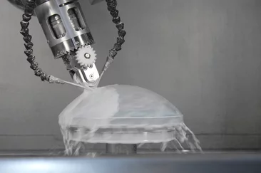 Eine optische Linse wird maschinell bearbeitet und mit Wasser und Sand gestrahlt
