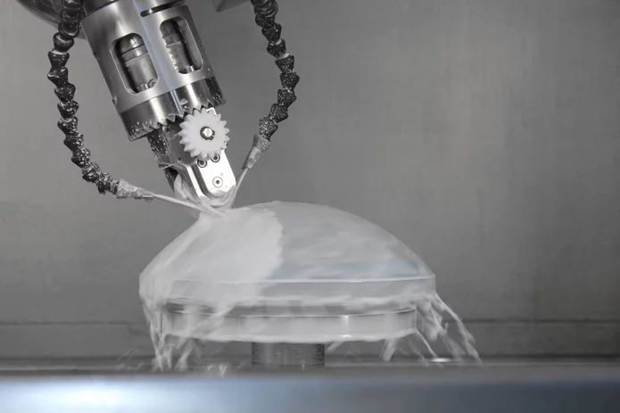 Eine optische Linse wird maschinell bearbeitet und mit Wasser und Sand gestrahlt