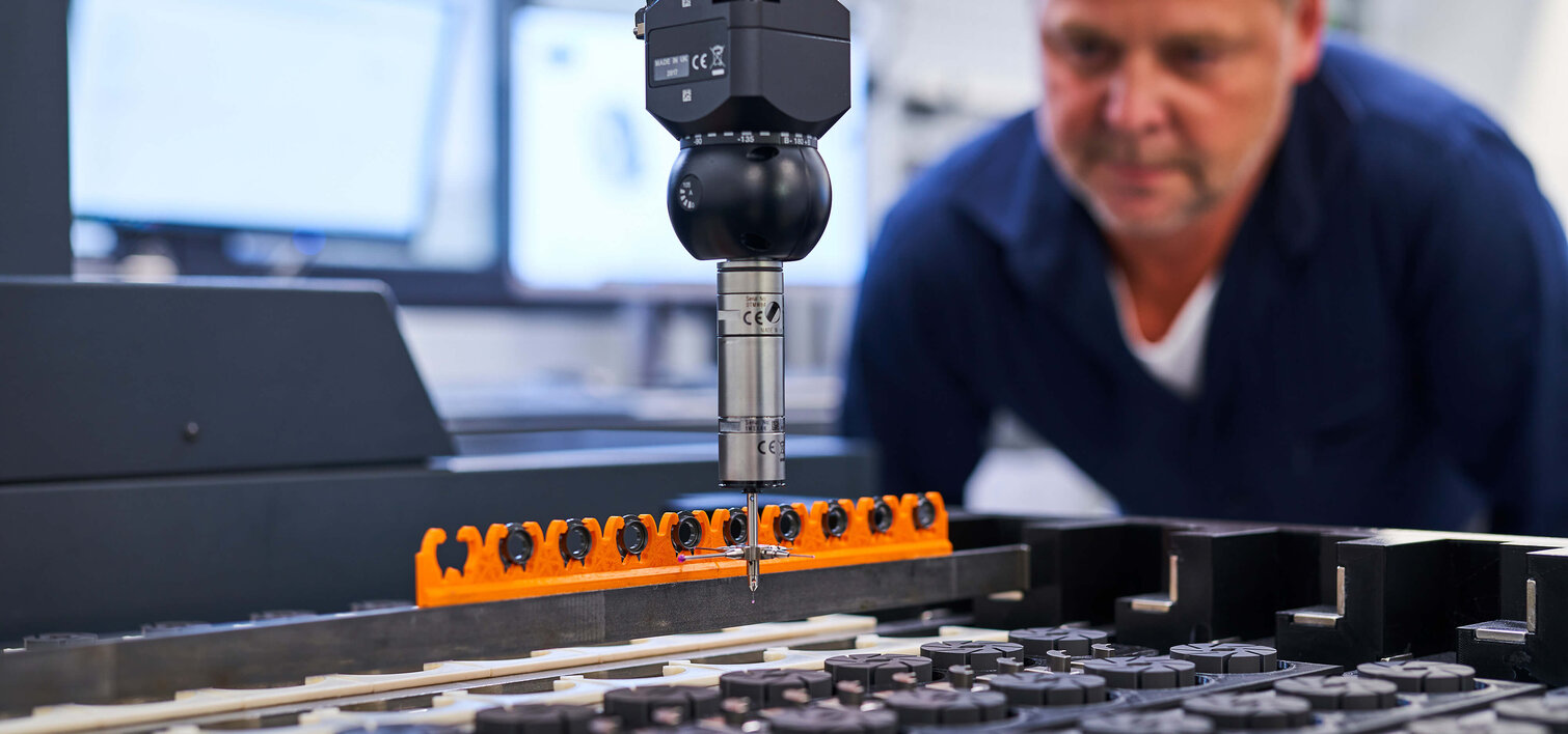 An employee supervises a probe for measurement, which is currently taking measurements on a workpiece