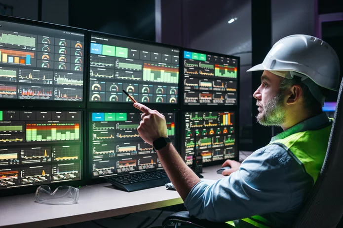  man in helmet sitting in front of surveillance monitors