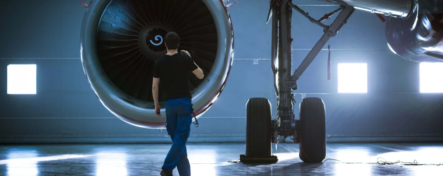 Aircraft mechanic working on the turbine of an airplane and inspecting it with a flashlight