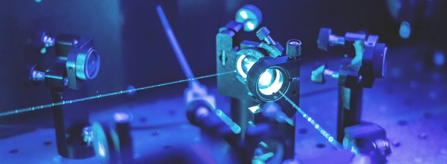  The inside of a laser apparatus, several mirrors and a laser beam shining through the mirrors inside the machine.