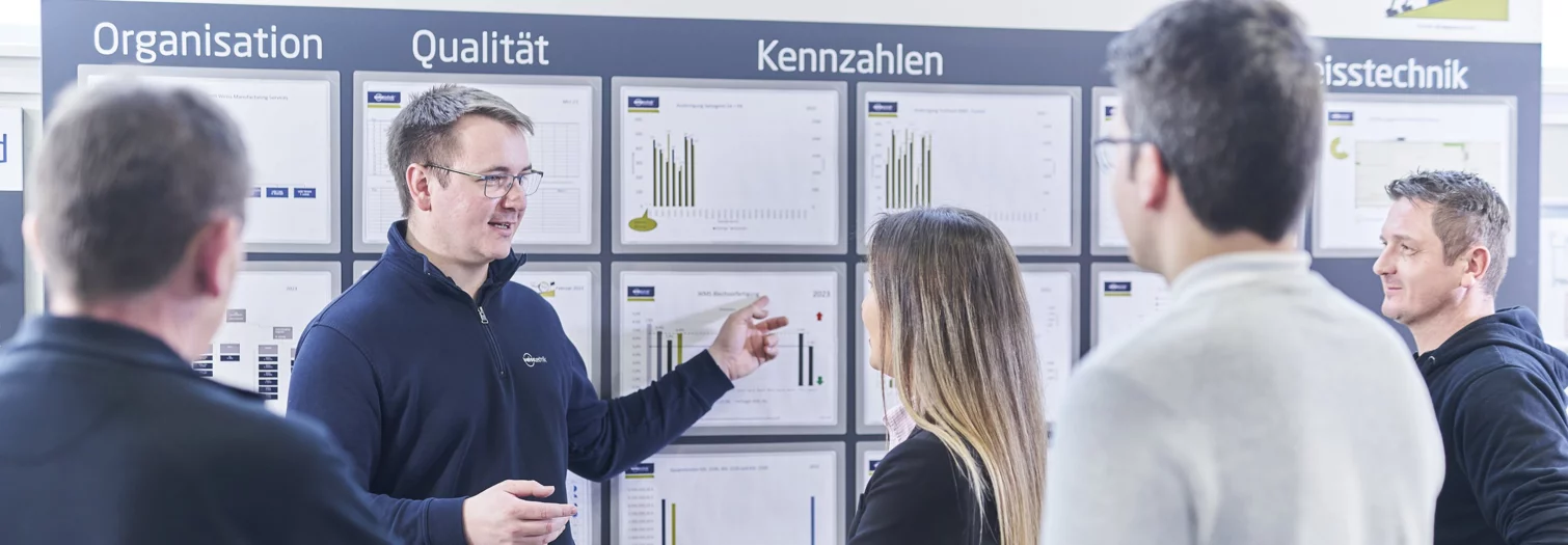 Mitarbeiter der Schunk Group bei einer Besprechung zu Kennzahlen vor einem Whiteboard mit verschiedenen Grafiken und Informationen