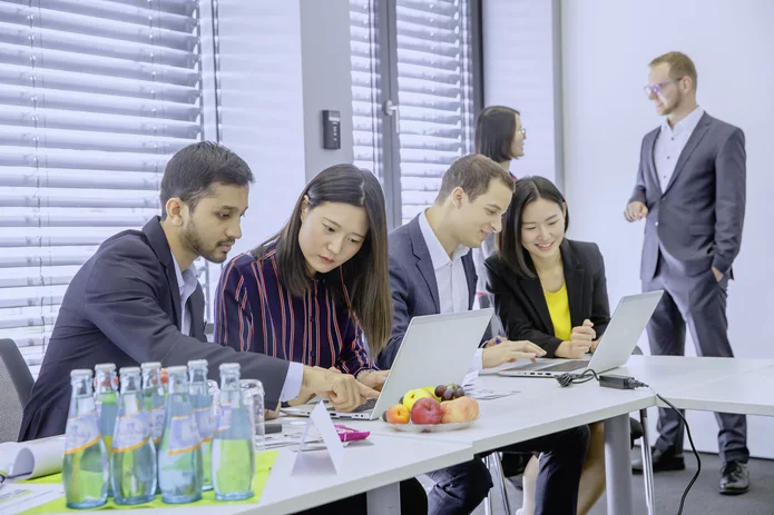 Eine diverse Gruppe verschiedener Nationalitäten und Hautfarben arbeitet gemeinsam in einem Meeting zusammen 