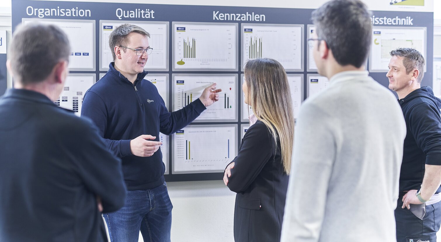  Schunk Group employees at a meeting on key figures in front of a whiteboard with various graphics and information