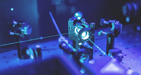 Das innere einer Laser Apparatur, mehrere Spiegel und ein Laserstrahl, welcher durch die Spiegel innerhalb der Maschine strahlt